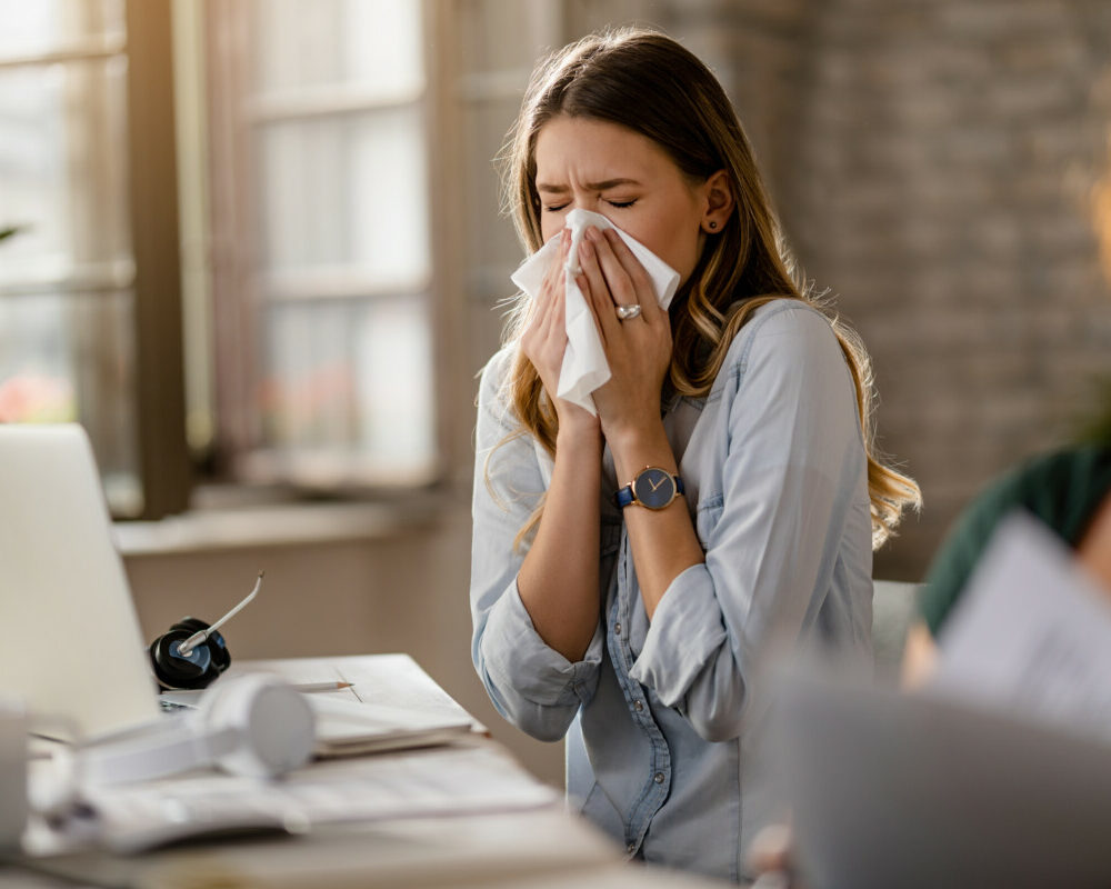 jeune-femme-d'affaires-malade-reniflant-un-tissu-en-travaillant-au-bureau