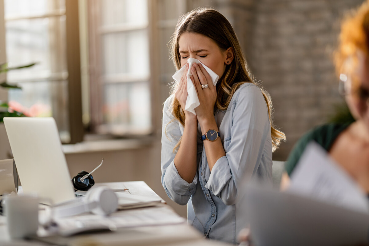 jeune-femme-d'affaires-malade-reniflant-un-tissu-en-travaillant-au-bureau