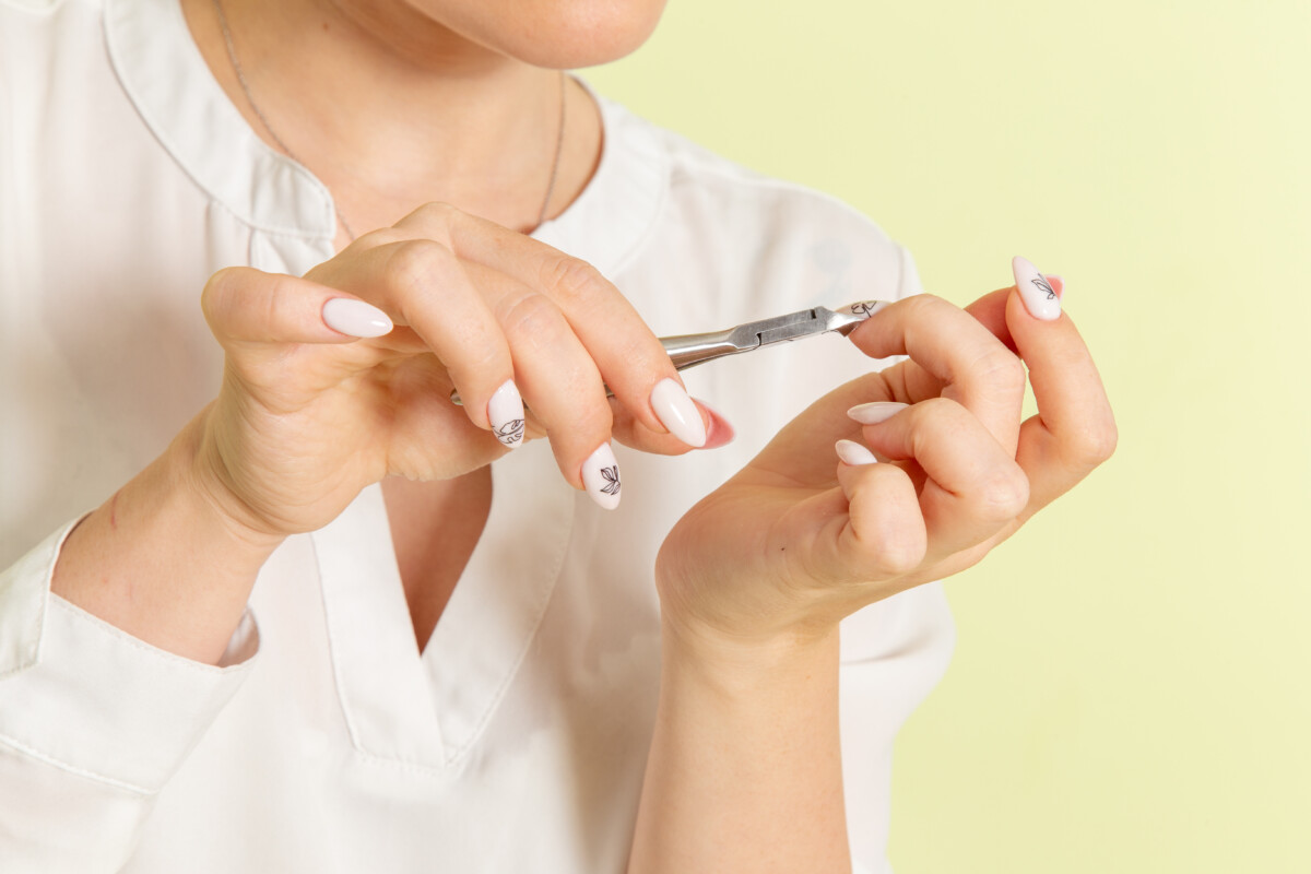 vue-devant-jeune-femme-attractive-chemise-blanche-fixant-les-ongles-de-la-surface-verte