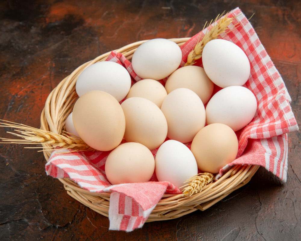 vue-devant-oeufs-de-poule-blancs-au-côté-du-panier-avec-serviette-surface-foncée