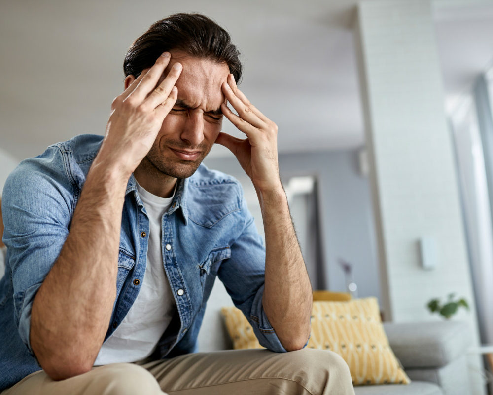 low-angle-view-distraught-man-holding-his-head-pain-while-sitting-living-room