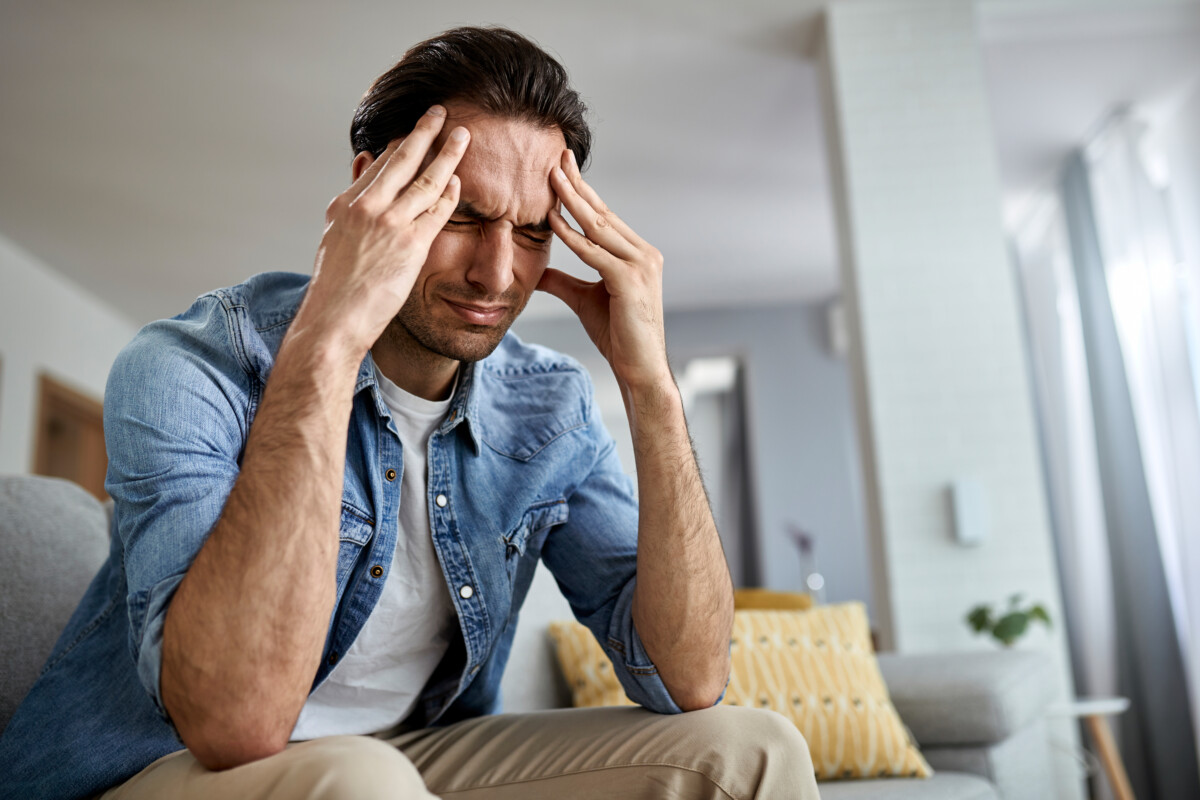 low-angle-view-distraught-man-holding-his-head-pain-while-sitting-living-room