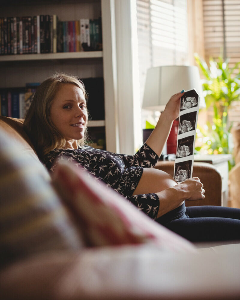 portrait-pregnant-woman-looking-sonography-living-room