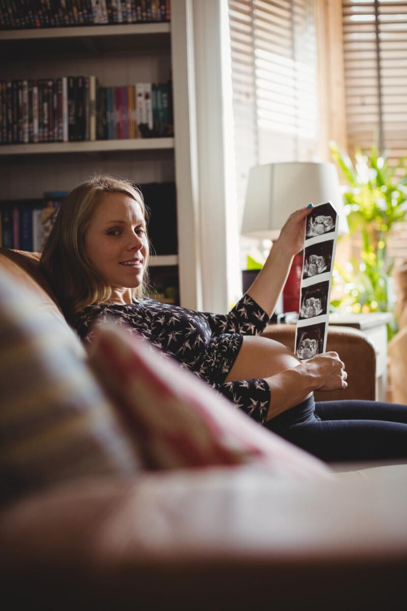 portrait-pregnant-woman-looking-sonography-living-room