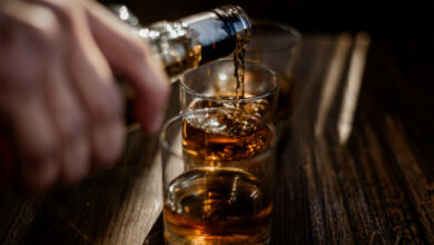 pouring-strong-alcohol-drink-into-glasses-which-are-wooden-table