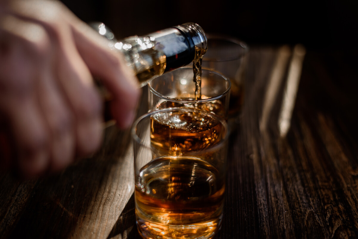 pouring-strong-alcohol-drink-into-glasses-which-are-wooden-table