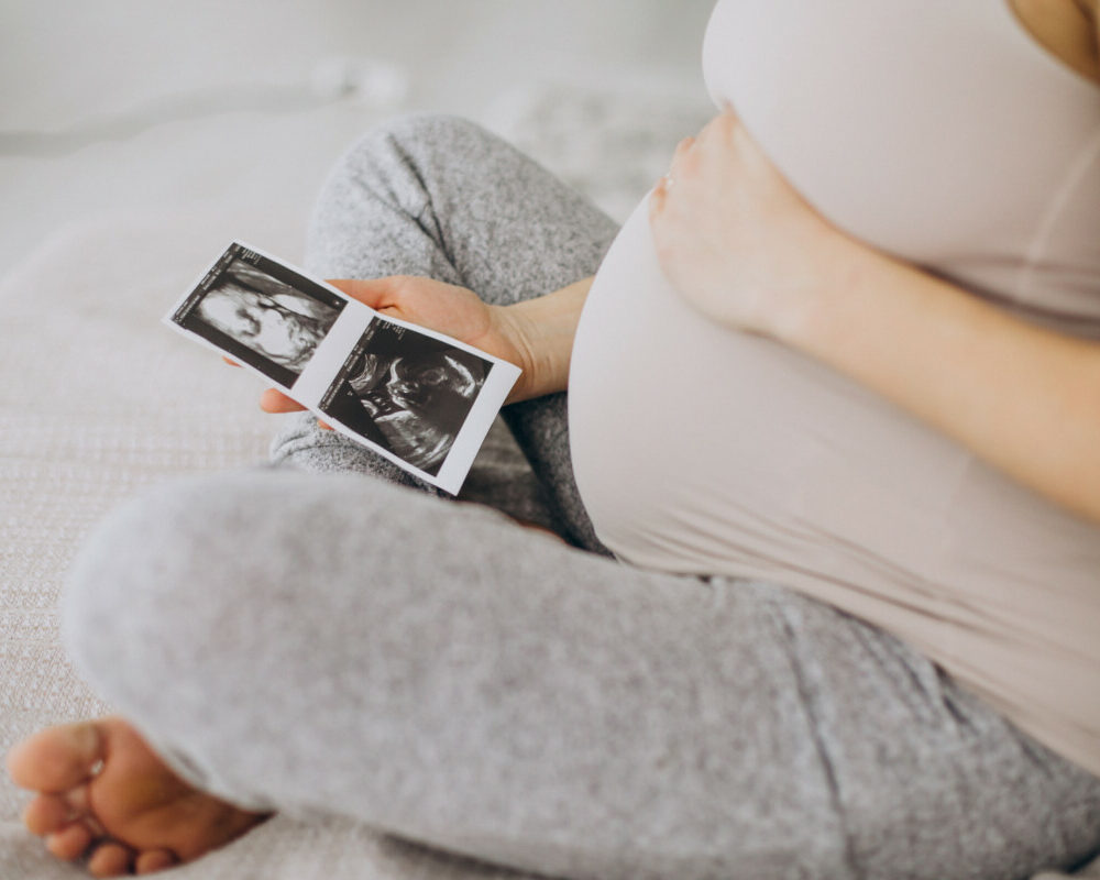 pregnant-woman-with-ultrasound-photo-sitting-bed