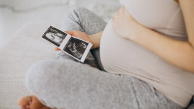 pregnant-woman-with-ultrasound-photo-sitting-bed