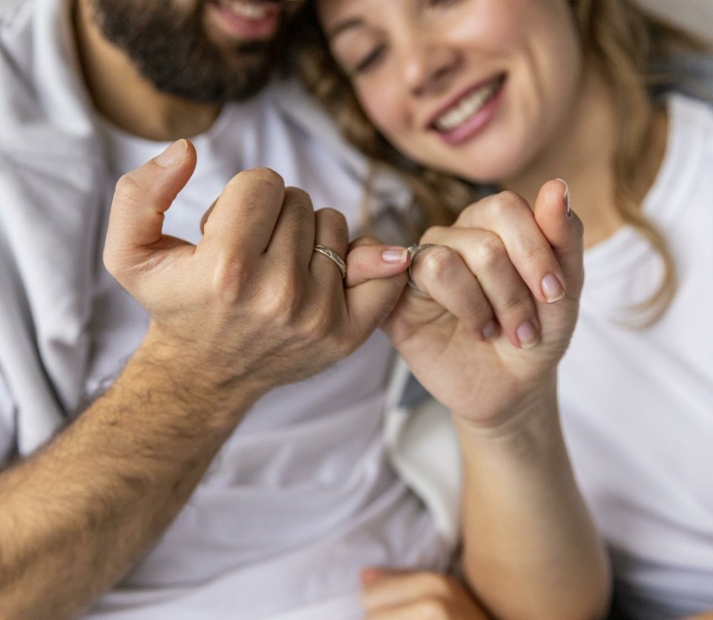 romantic-couple-locking-pinkies-sofa-home