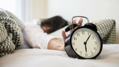 sleepy-woman-reaching-holding-alarm-clock