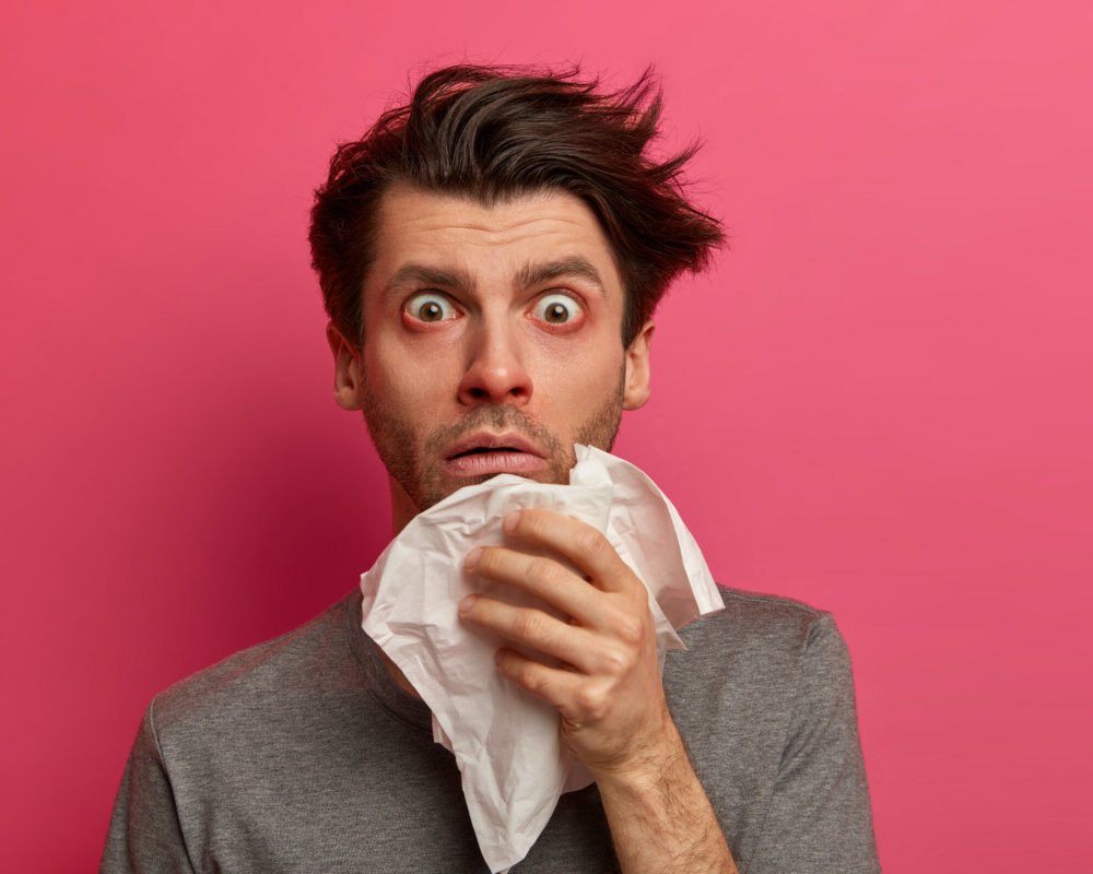 stunned-sick-man-has-flu-virus-allergy-respiratory-red-watery-eyes-blows-nose-tissue-finds-out-about-serious-disease-poses-pink-wall-health-medicine-symptoms-concept