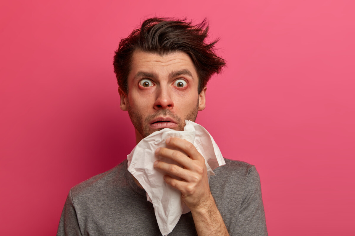 stunned-sick-man-has-flu-virus-allergy-respiratory-red-watery-eyes-blows-nose-tissue-finds-out-about-serious-disease-poses-pink-wall-health-medicine-symptoms-concept