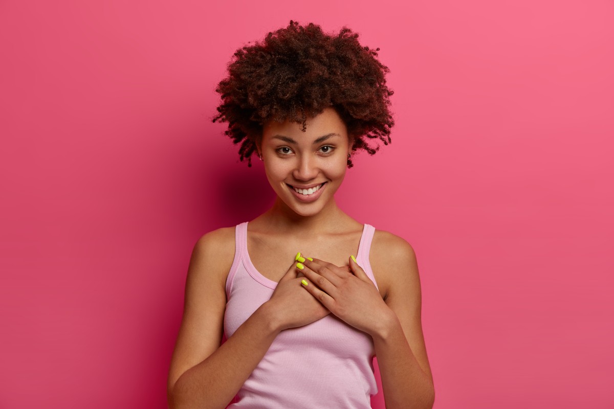 touched-pleased-lovely-woman-hears-heartwarming-story-presses-hands-heart-feels-thankful-promises-you-smiles-gently-wears-casual-clothes-appreciates-nice-gift-poses-rosy-wall